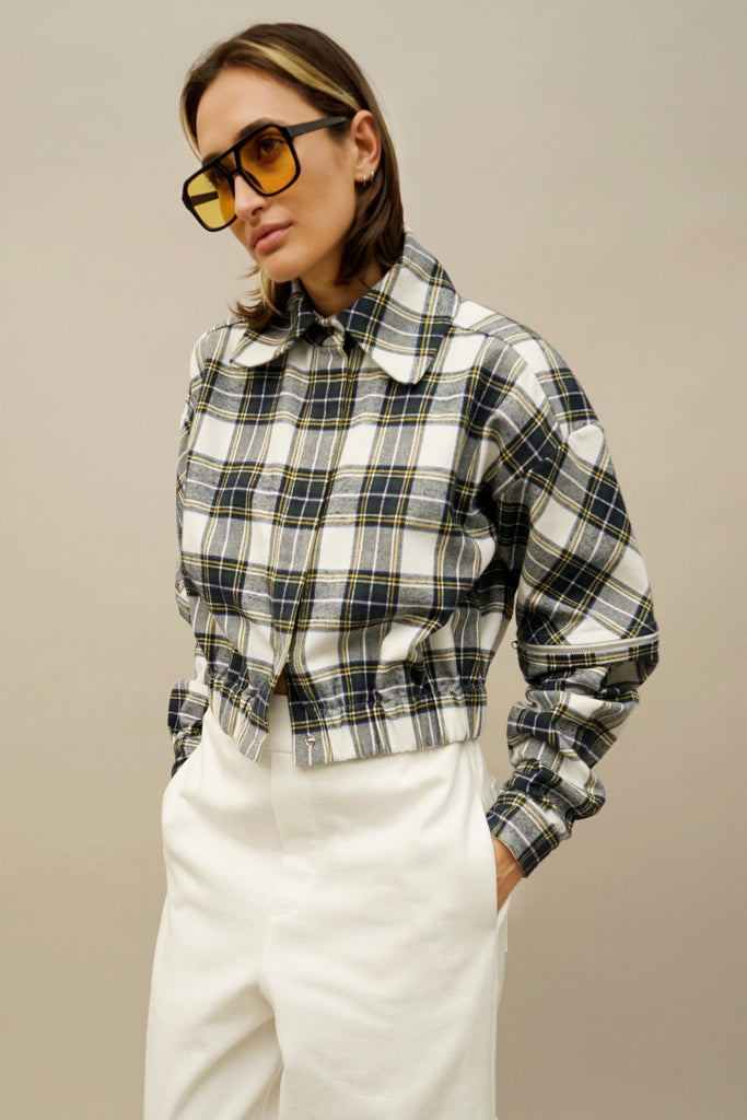 Closeup of NINObrand's plaid jacket paired with utility-style white pants and bold eyewear.