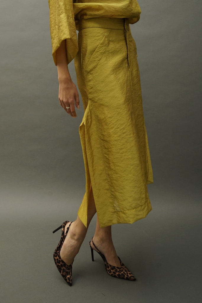 Side profile highlighting sheer volume of mustard skirt paired with a fashion forward matching shirt.