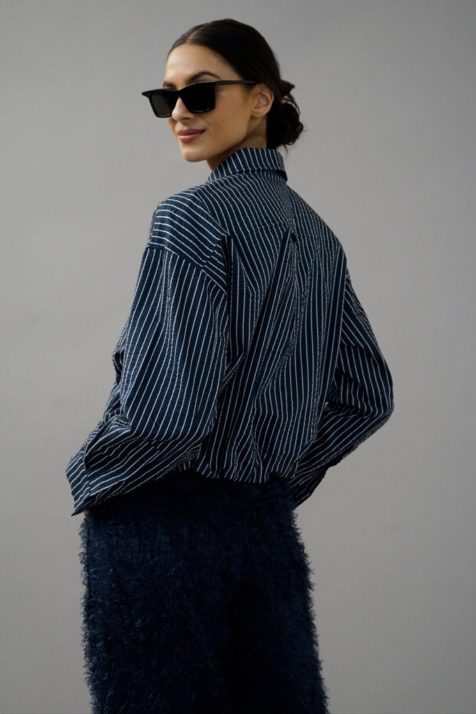 Model wearing a navy striped long-sleeve button-up shirt paired with textured navy pants.