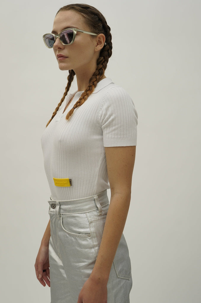 Model showcasing NINObrand short sleeve bodysuit with polo collar, paired with metallic jeans