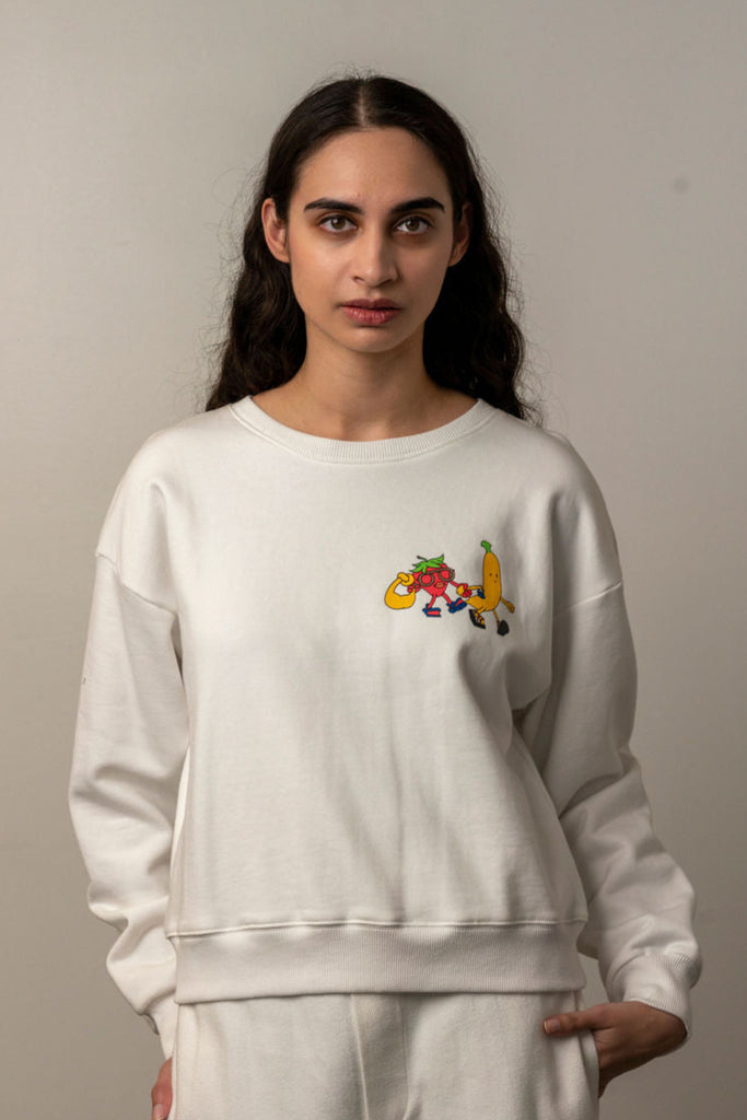 Woman wearing a white Unbranded crewneck sweatshirt with colorful fruit cartoon graphic on chest