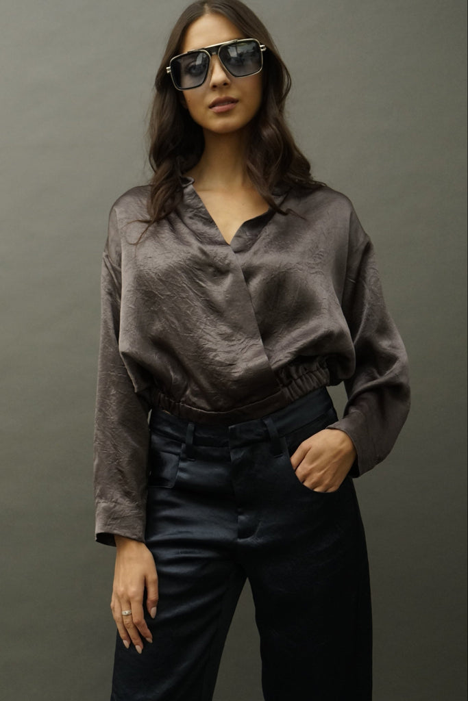 Front view of Idle olive satin wrap blouse with V-neckline, studio backdrop