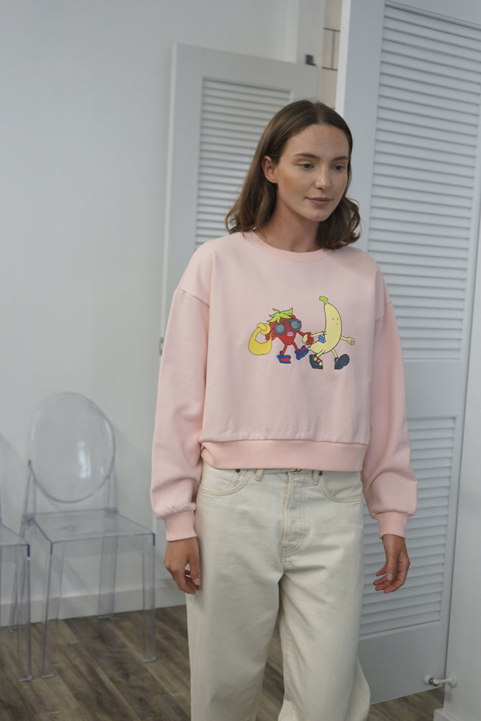 A model wearing the Pink Hypebeast sweatshirt, showing the front with the large, colorful graphic of a fashionable strawberry and banana.