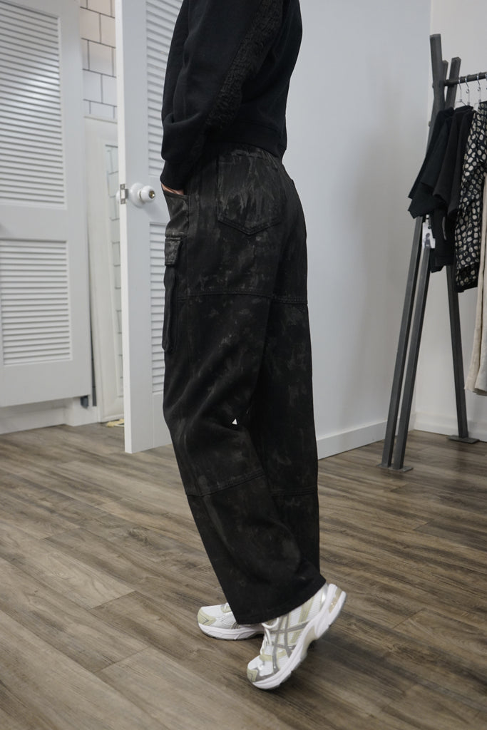  A side view of the model, showcasing the black hand painted cargo pockets and the fit of the pants.