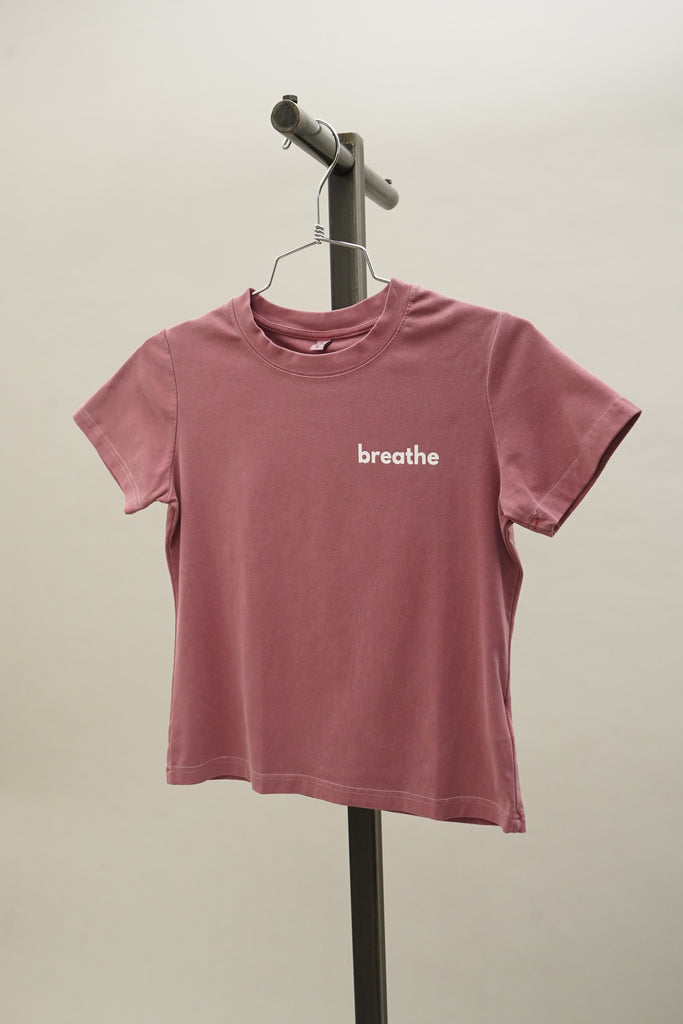 Rose form-fitting short sleeve crew neck t-shirt with the word ‘breathe’ printed on the front, presented on a soft neutral background.