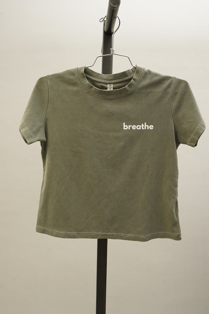 Olive form-fitting short sleeve crew neck t-shirt with the word ‘breathe’ printed on the front, shown on a neutral background.