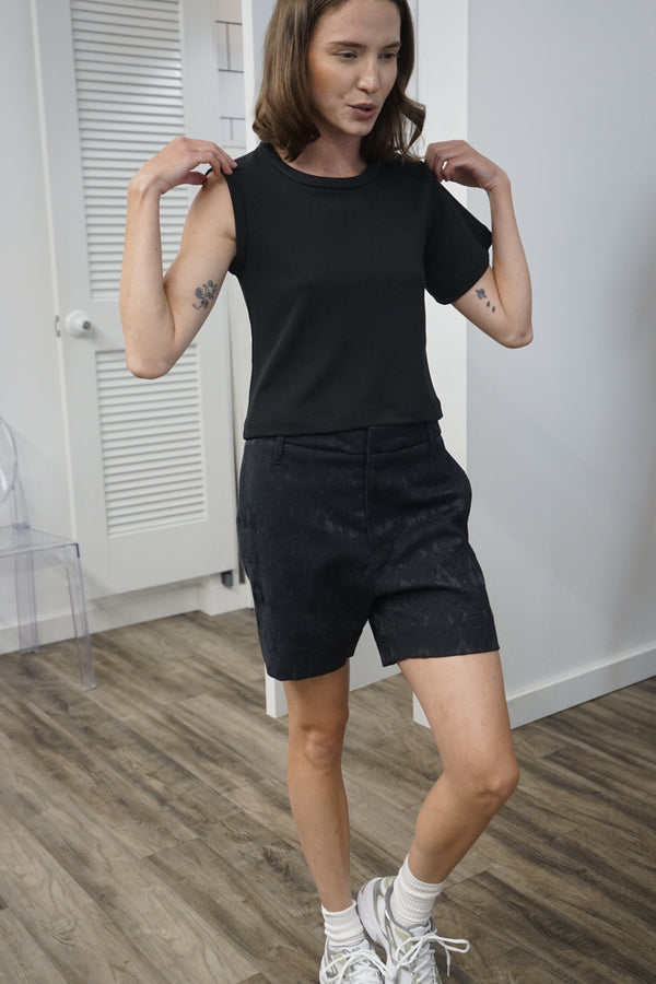 A video thumbnail showing a model moving or working out in the Clay tee to demonstrate the flexibility and moisture-wicking properties of the fabric.